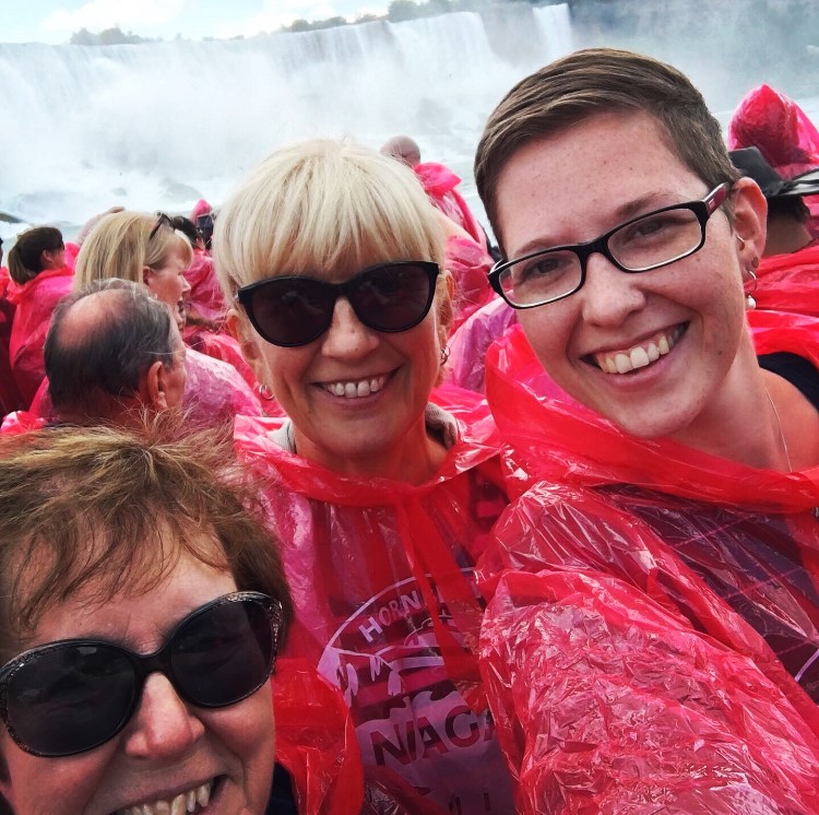 Group of people in red rain ponchos near a large waterfall.